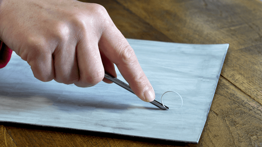 Dłoń pokazująca prawidłowy chwyt dłuta do linorytu podczas rzeźbienia na linoleum. 